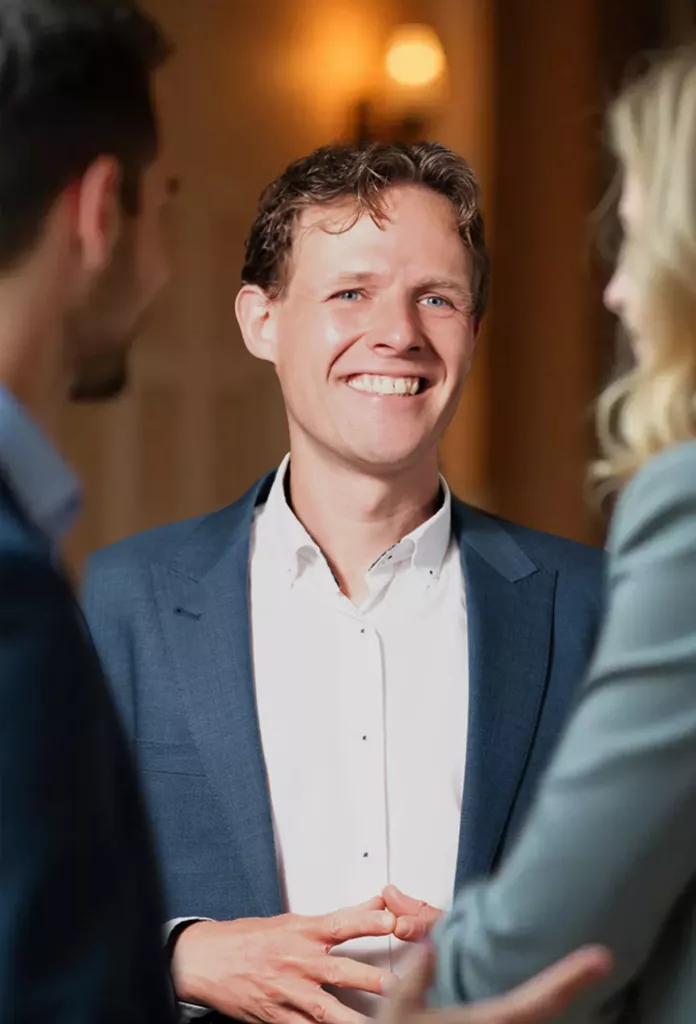 Lachende man in een blauw colbert in gesprek met twee mensen